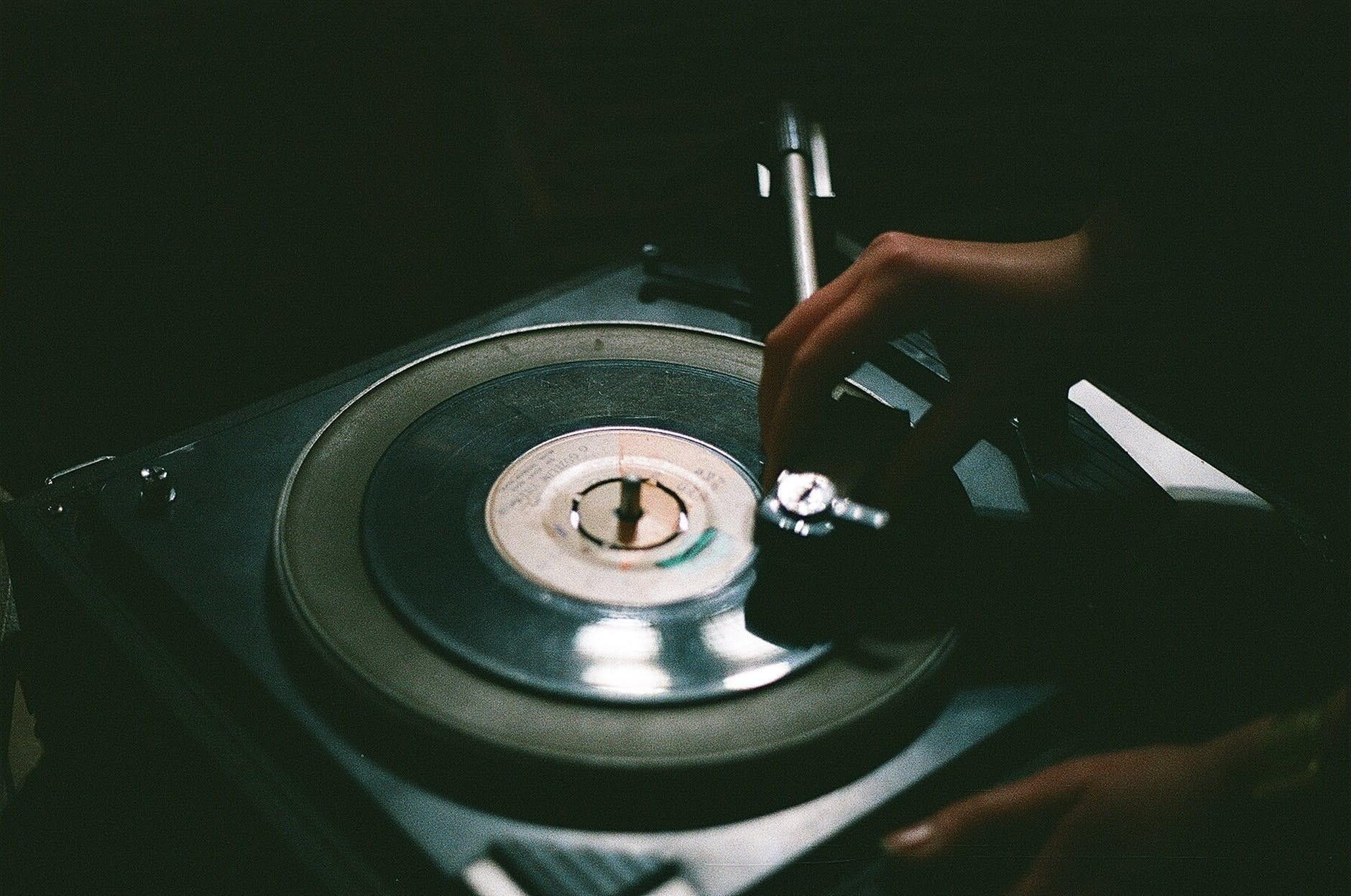 A hand lowers the record player stylus to start playing music